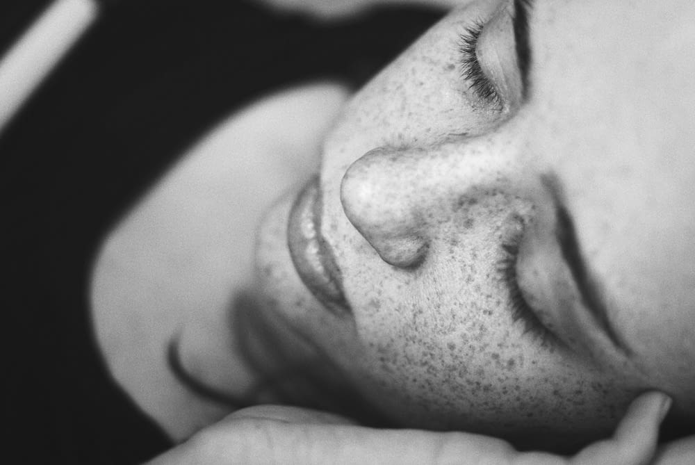 grayscale photo of woman's face with freckles