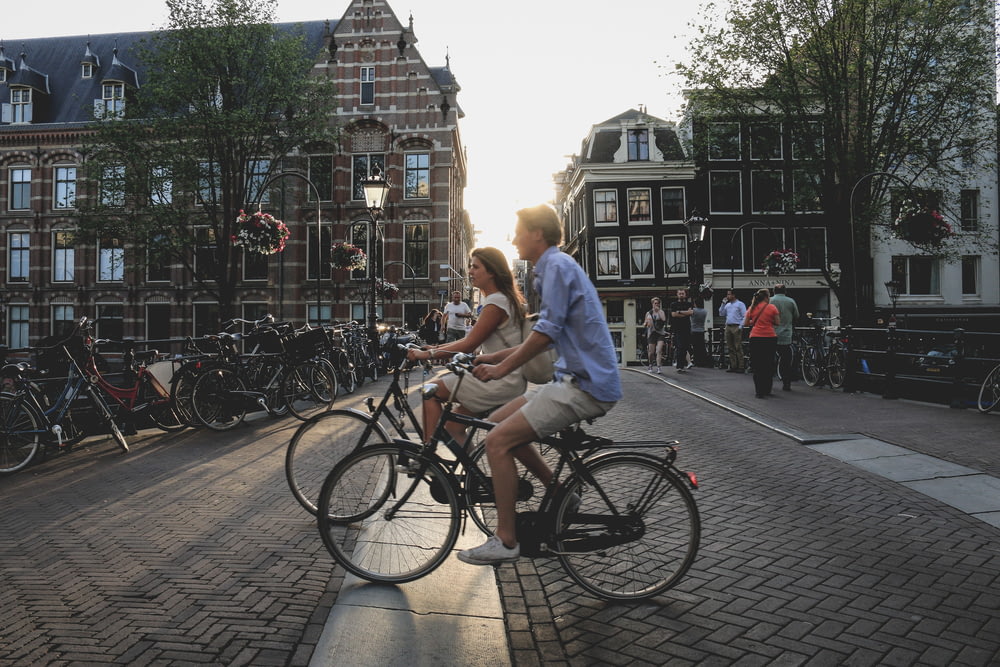 uomo e donna in bicicletta lungo la città durante il giorno