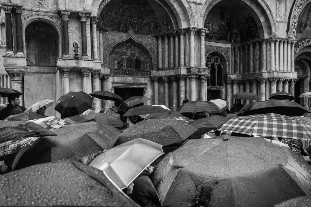 grayscale photo of people using umbrellas