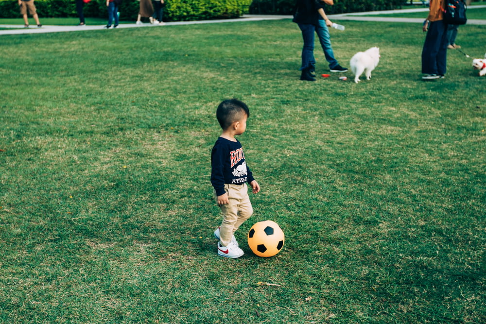 Junge spielt Fußball auf Rasenplatz