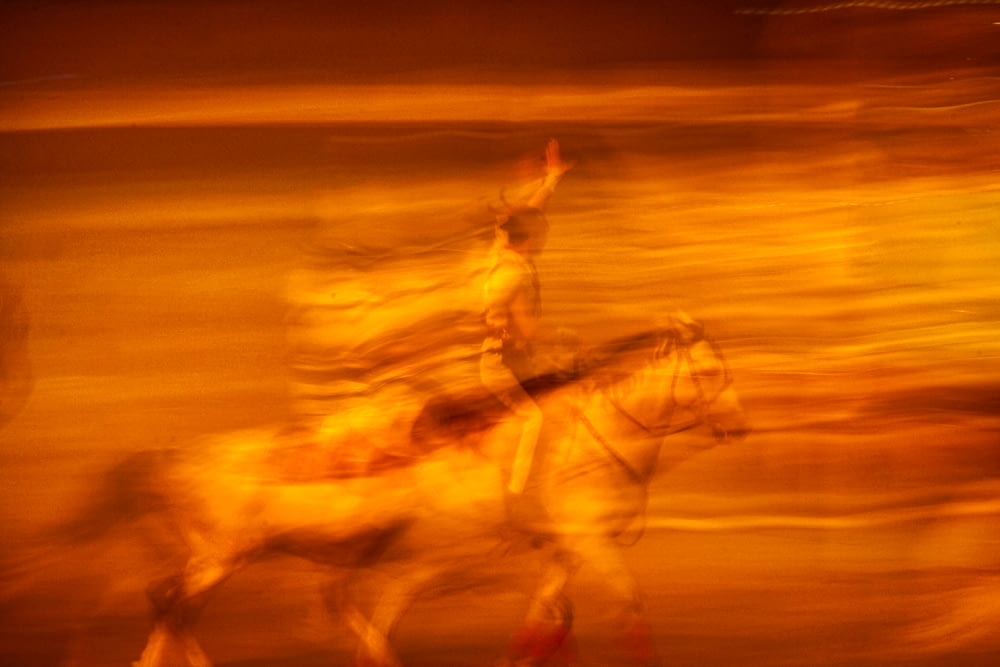 Una foto sfocata di un uomo che cavalca un cavallo