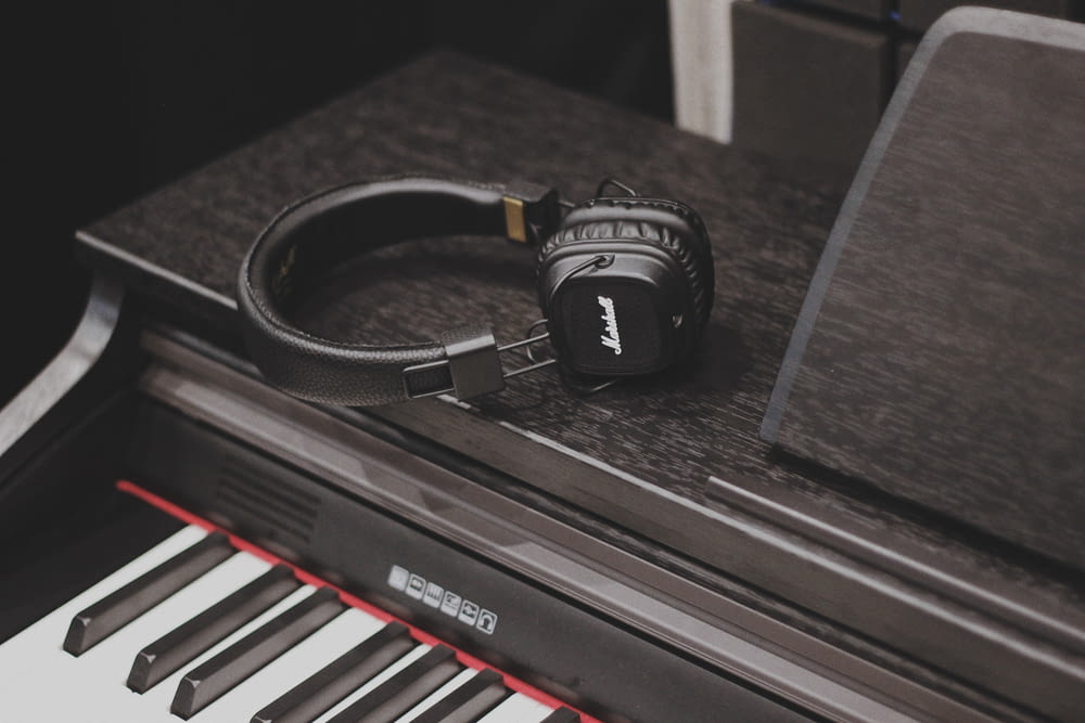 black and white Bluetooth headphones on top of black piano