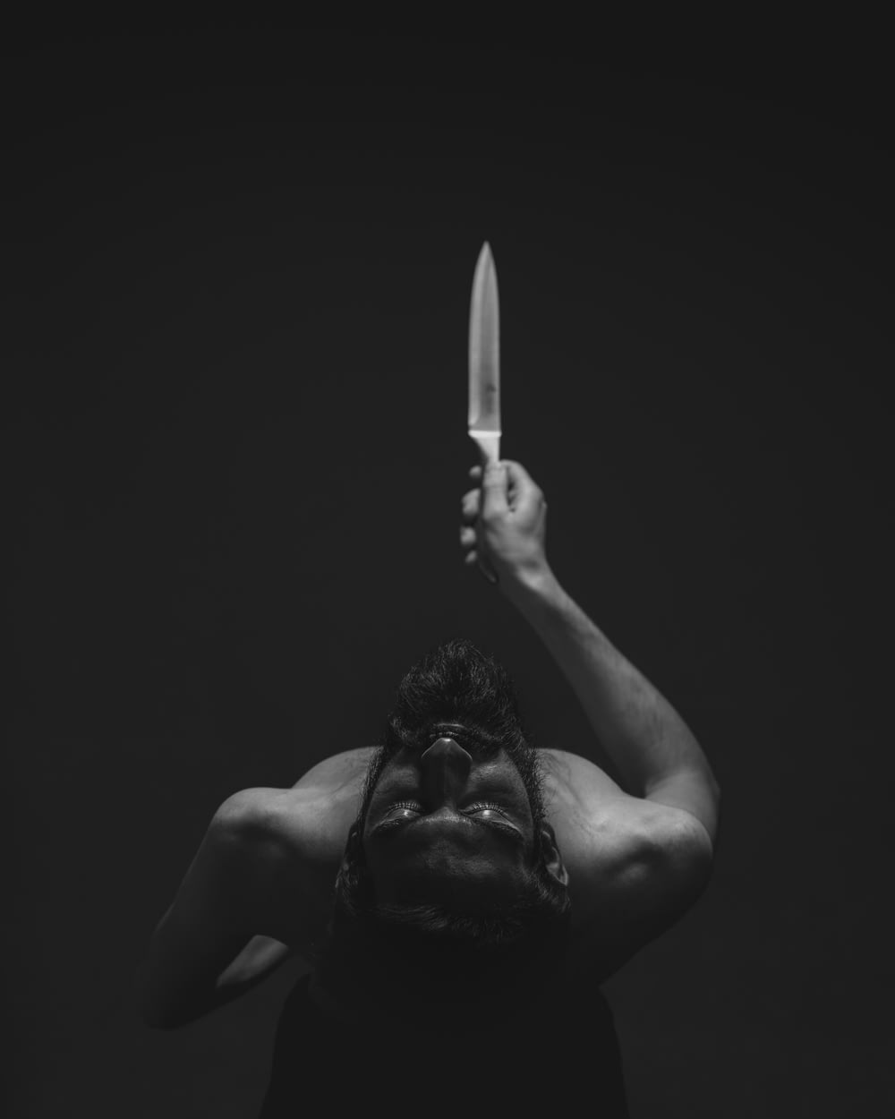 grayscale photography of man holding knife