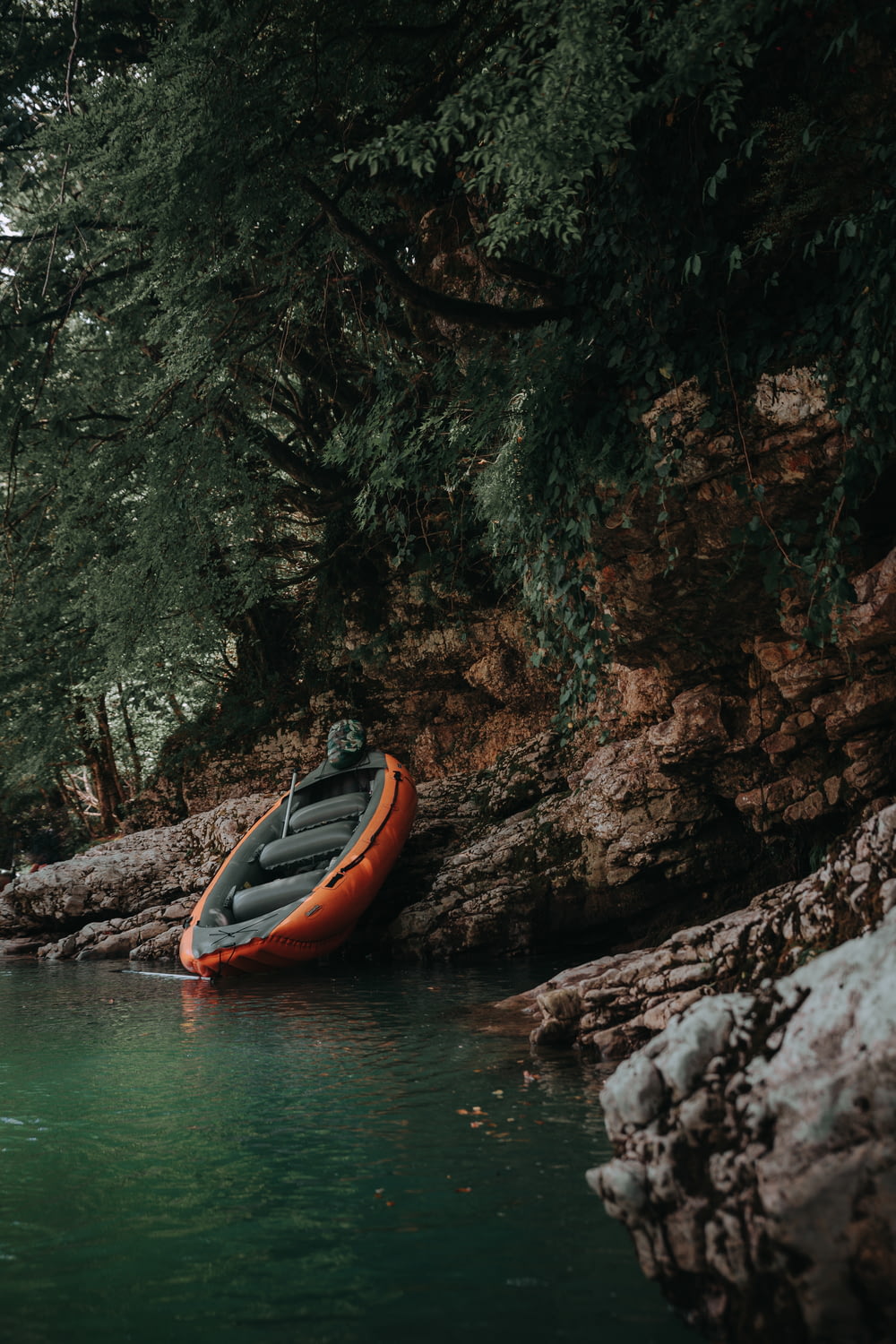 orange inflatable raft on brown stone under green tree