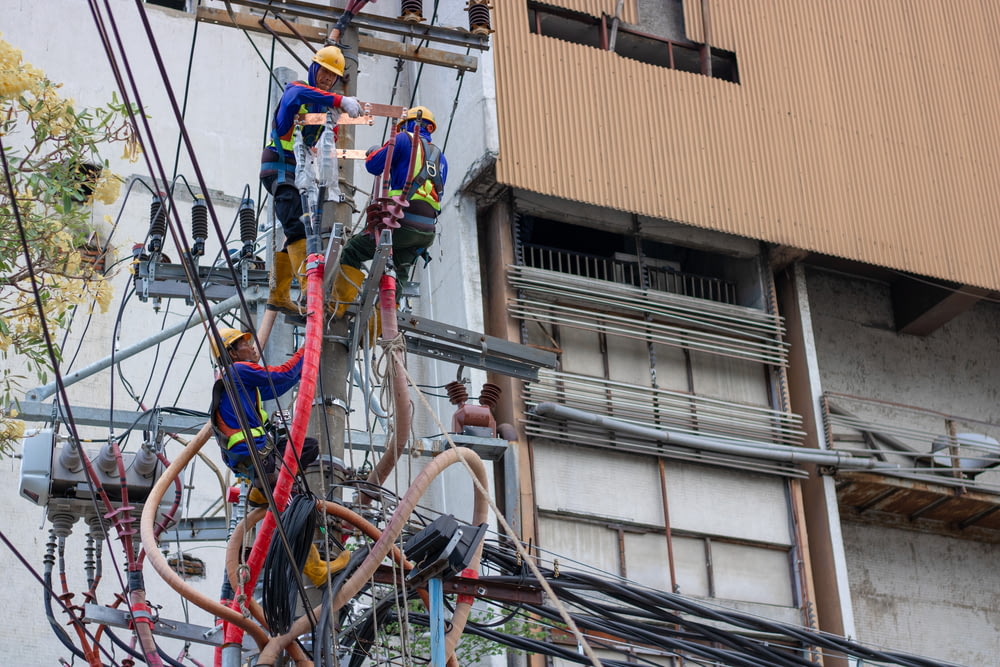 group of people fixing the wires on post