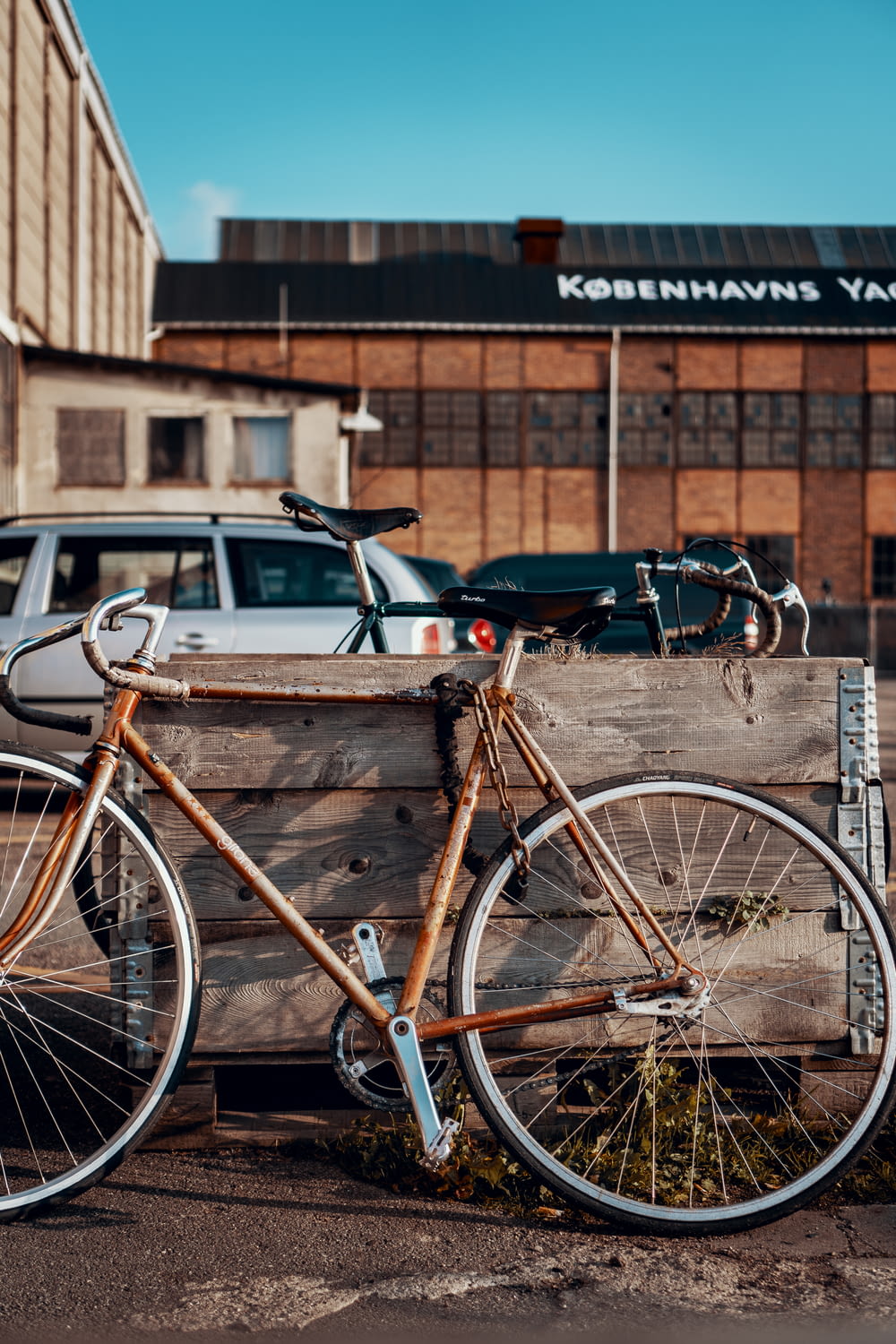 brown bicycle parked beside wooden panel during daytime