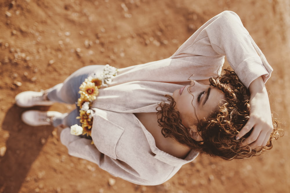 茶色の土の上に立つベージュのトップを着た女性 ハイアングル写真
