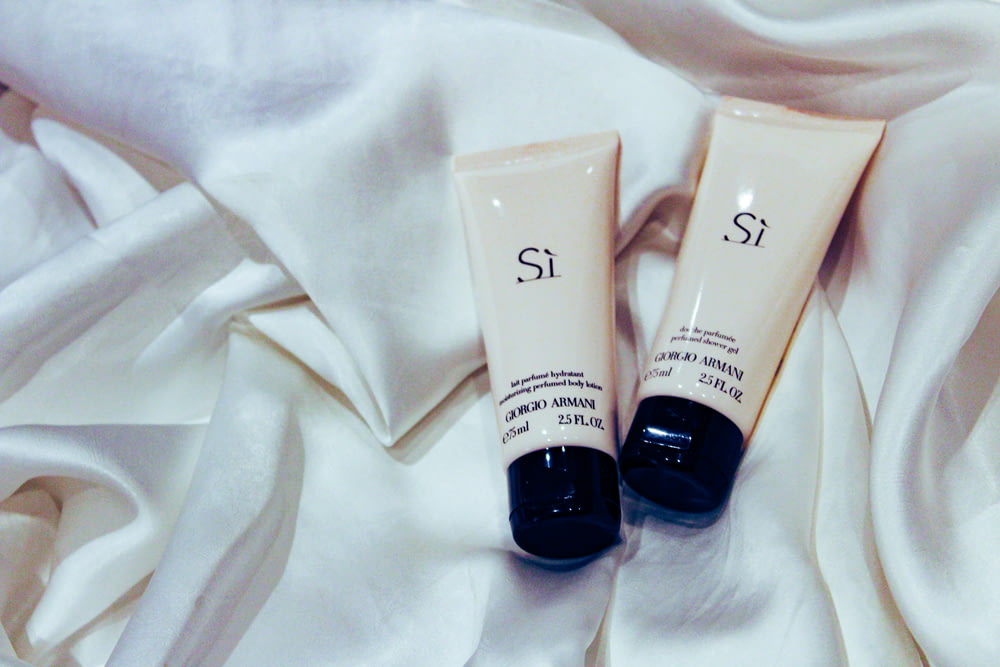 two unopened Si cosmetic soft-tubes on white textile