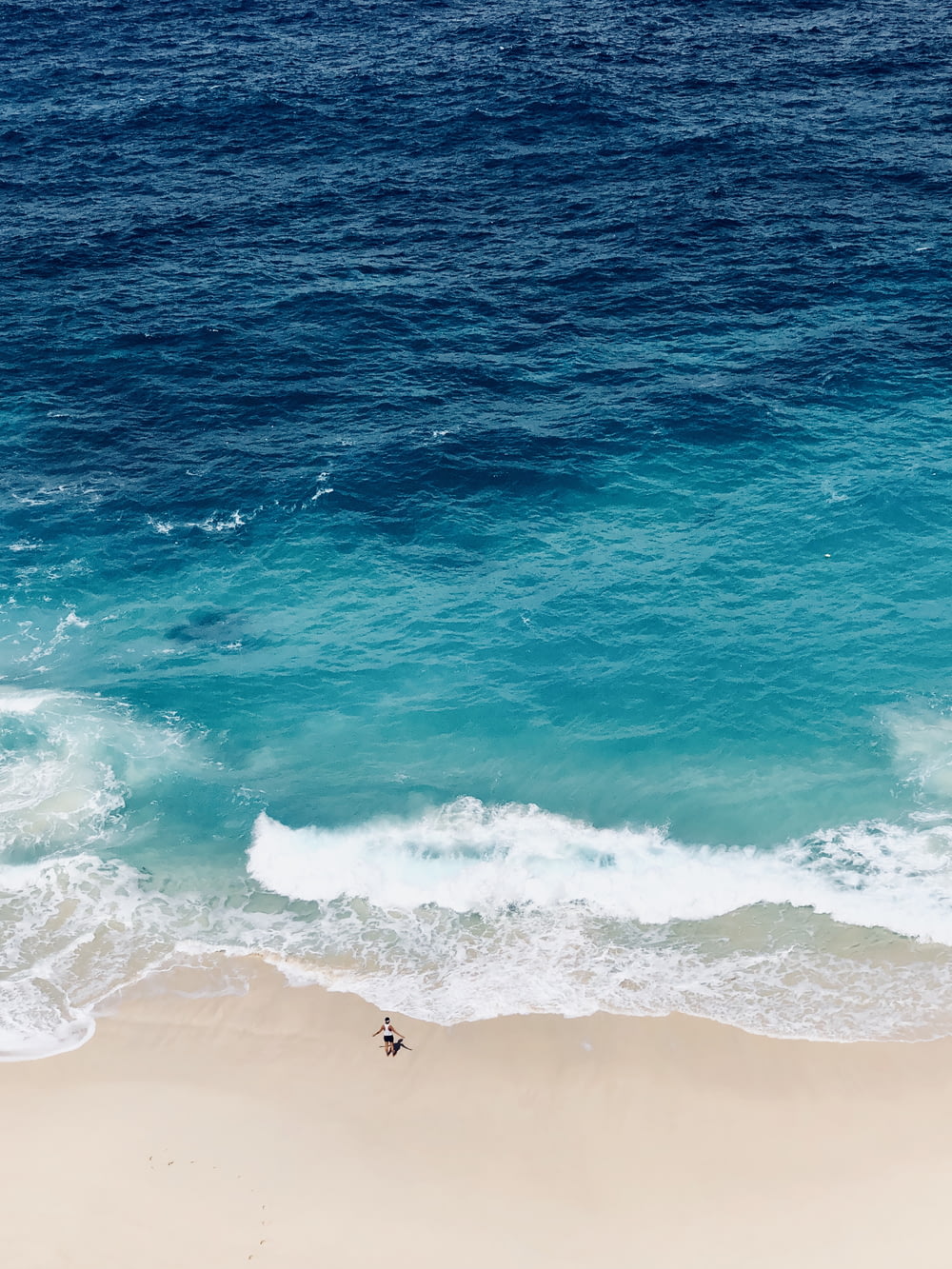 fotografia aerea di una persona in piedi in riva al mare