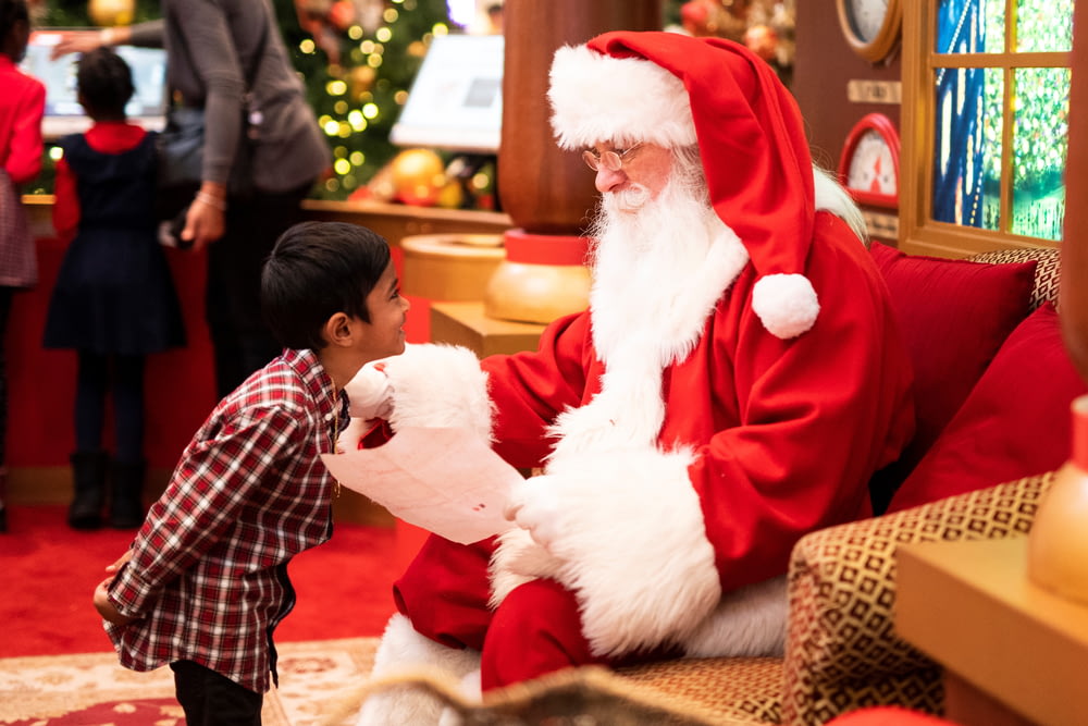 garçon debout devant un homme portant un costume de Père Noël