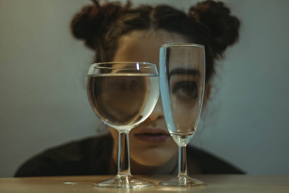 two clear drinking glasses on top of the table near woman