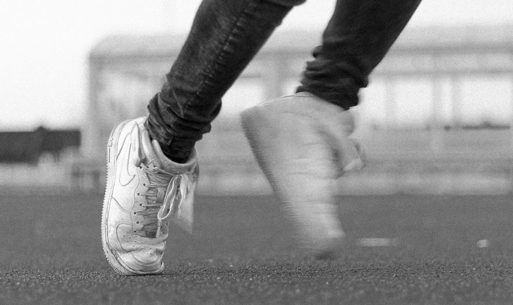 photo en niveaux de gris d’une personne portant des chaussures à lacets Nike