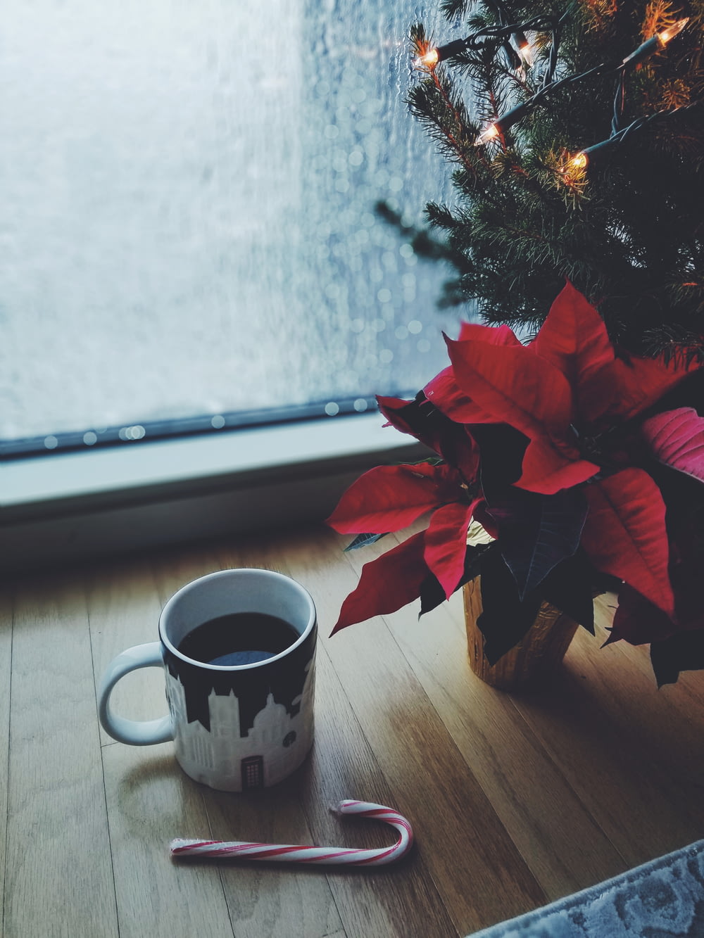 窓際のクリスマスツリーのそばにあるマグカップのコーヒー