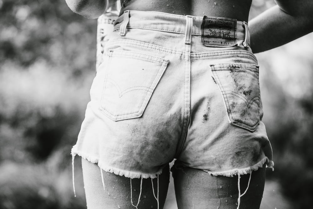 person wearing denim short-shorts in grayscale photography