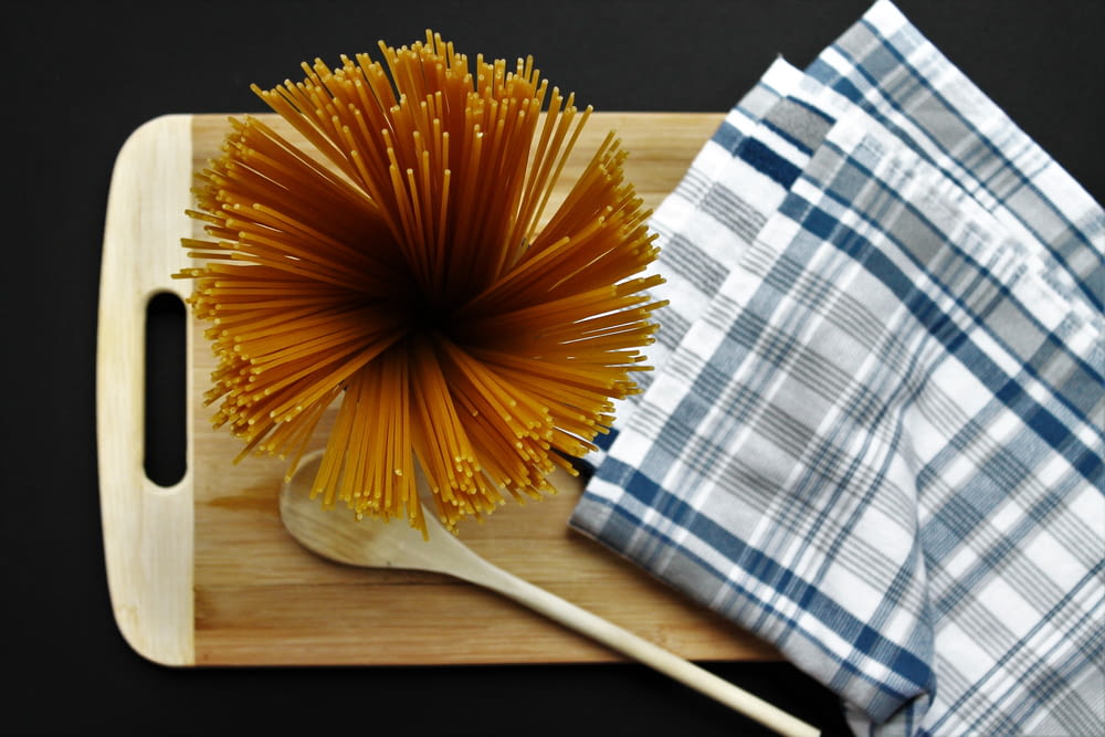 spaghetti pasta, brown wooden ladle, and hand napkin on brown wooden chopping board