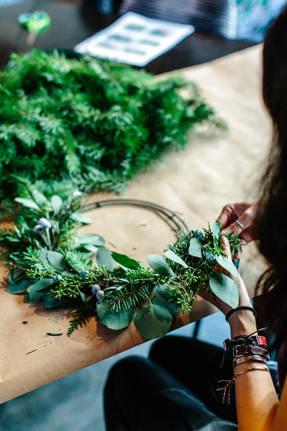 Frau macht grünen Blumenkranz auf dem Tisch