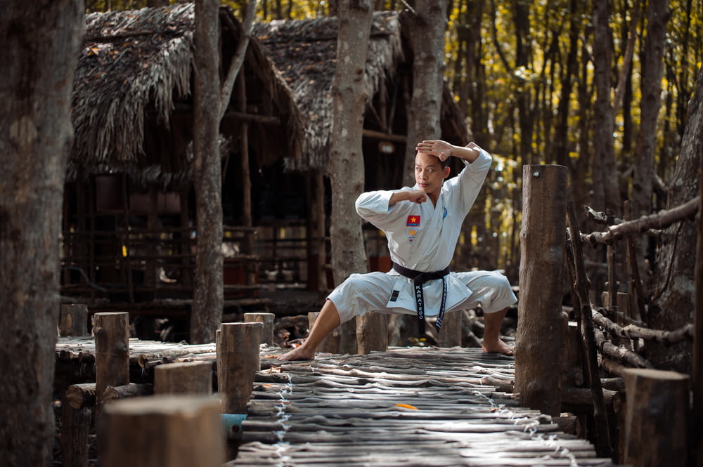 man wearing karate gi squatting on wooden dock