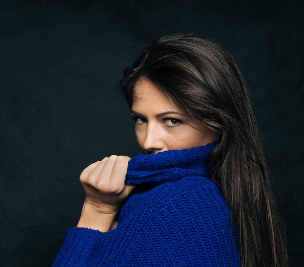 woman covering her mouth with blue sweaer