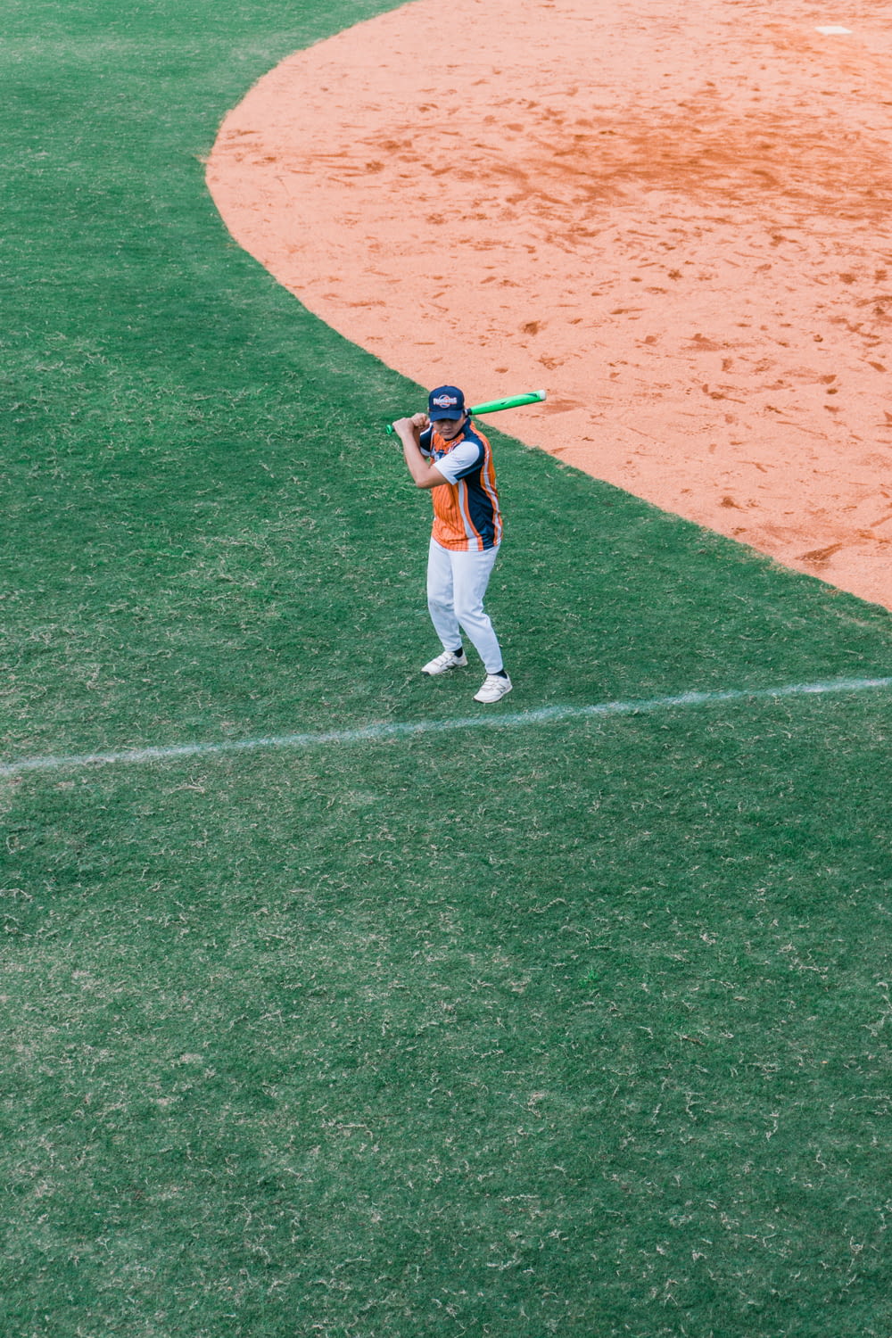 person holding baseball bat on green field