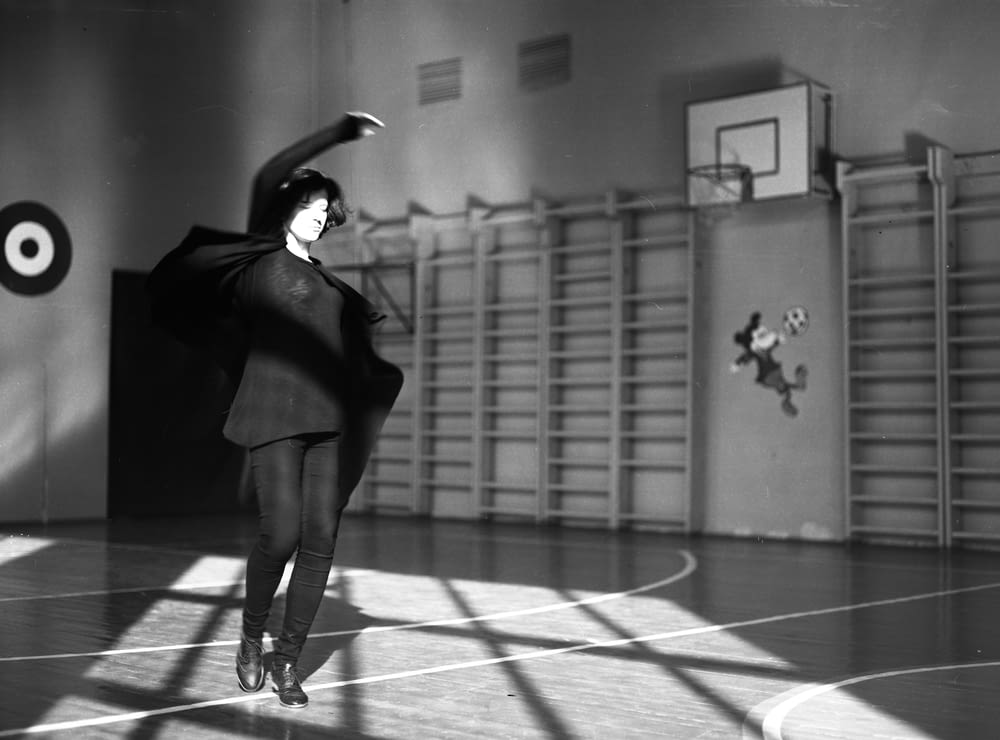 grayscale photography of woman standing in basketball court