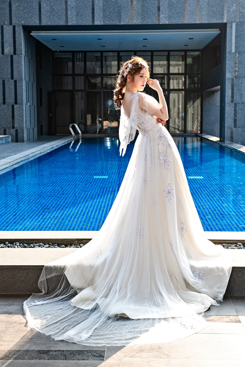 woman in white dress standing near swimming pool during daytime