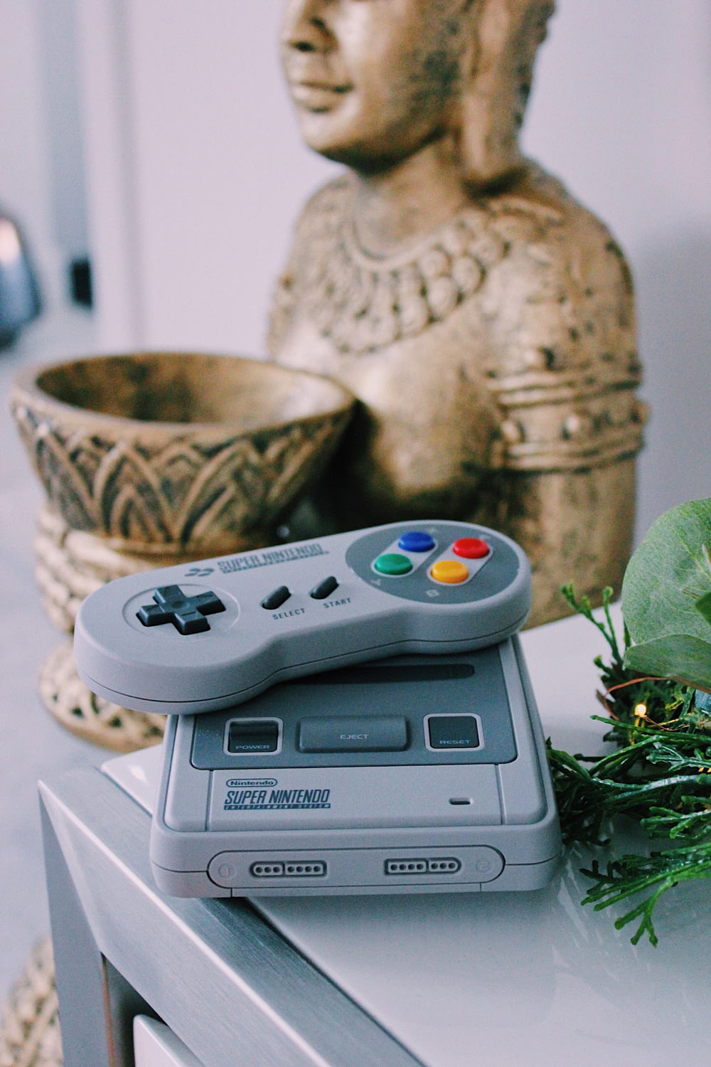 Consola de juegos Super Nintendo gris con controlador sobre la mesa