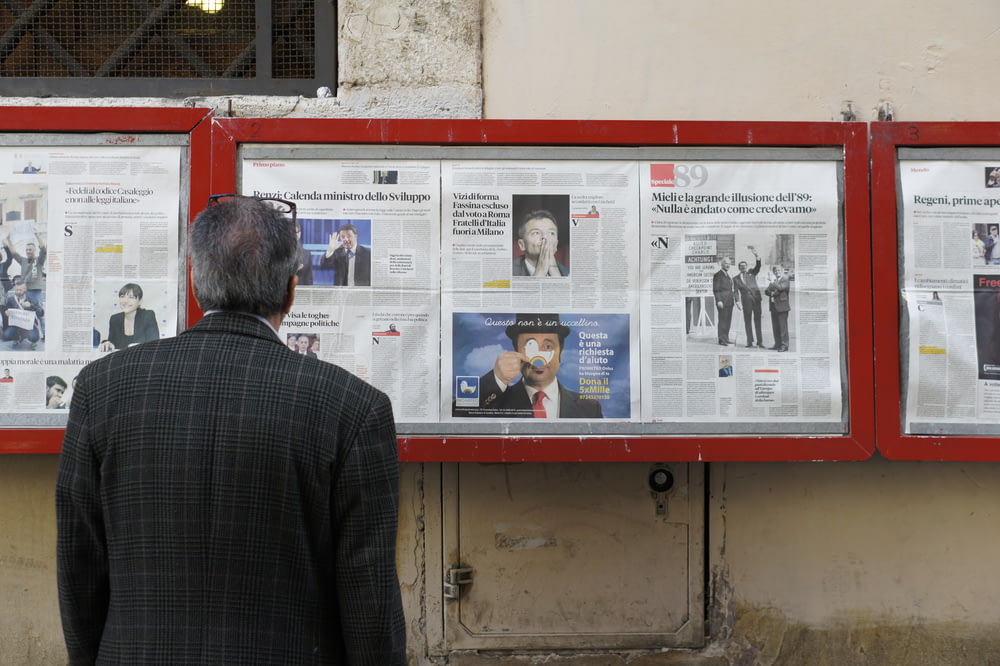 homme lisant un journal dans un tableau d’affichage