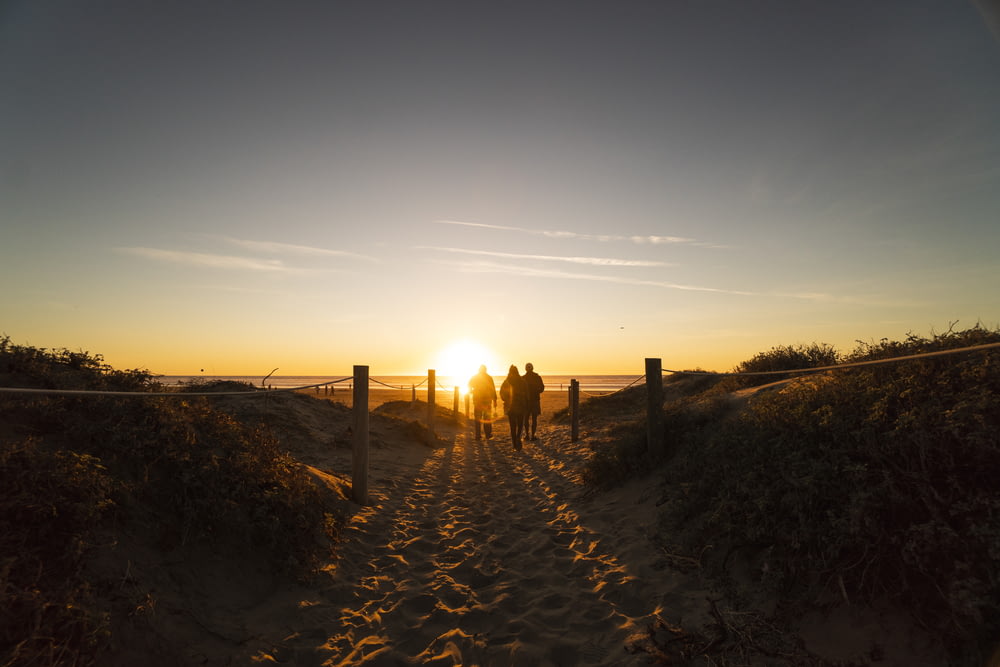 Tre persone che camminano sulle dune di sabbia vicino alla spiaggia