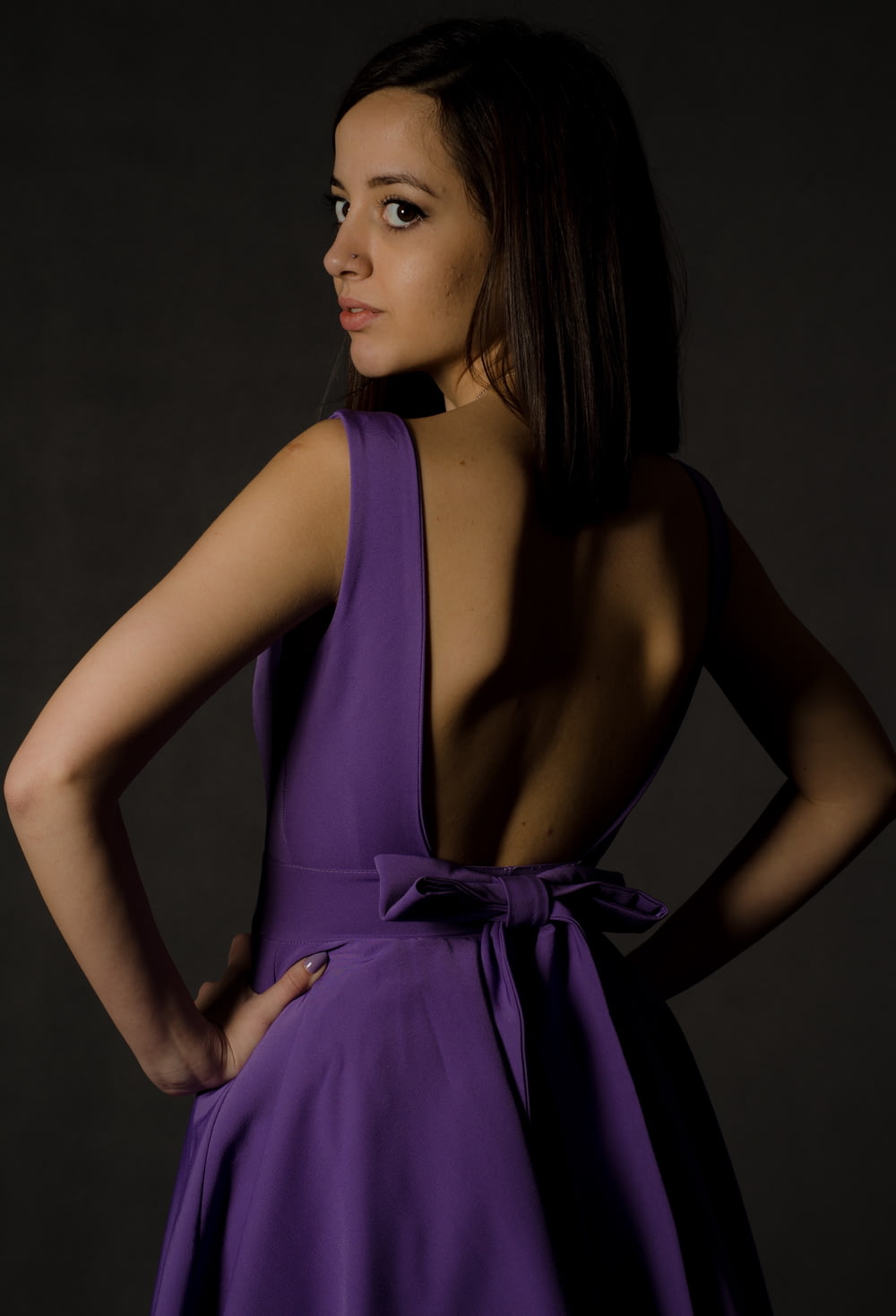 donna che indossa un vestito viola senza schienale che guarda indietro