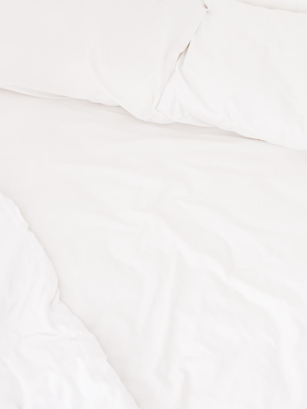 a close up of a bed with white sheets and pillows