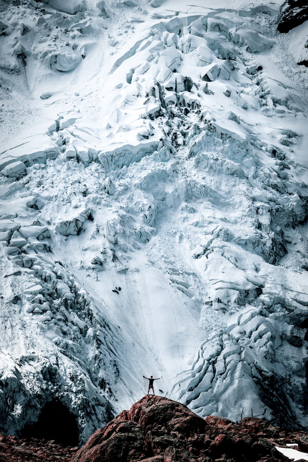 자연 사진에서 눈 덮인 산의 바위 앞에 서 있는 사람