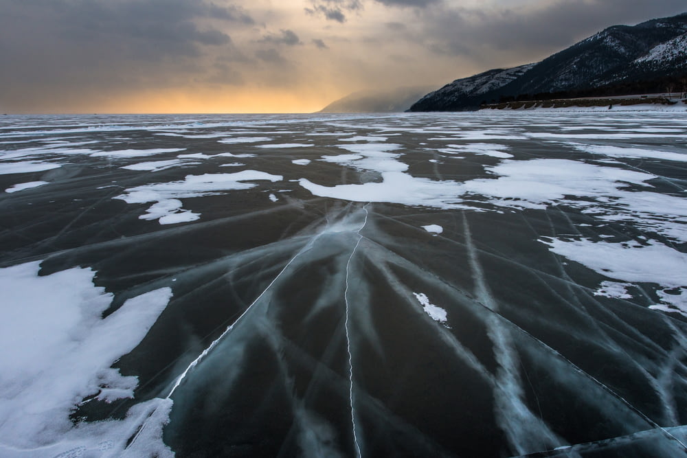 a large body of water covered in ice under a cloudy sky