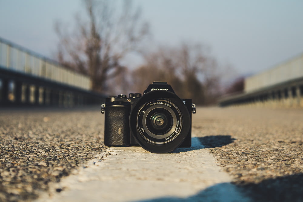 selective focus photography of black DSLR camera on gray concrete pavement during daytime