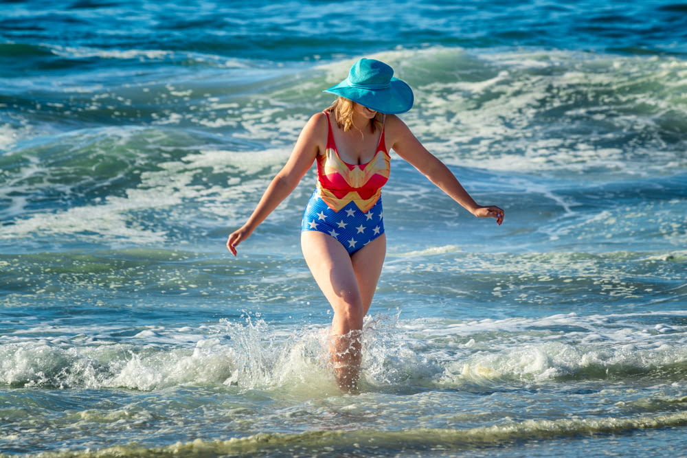 woman in wonder-woman bikini walks on sea waves