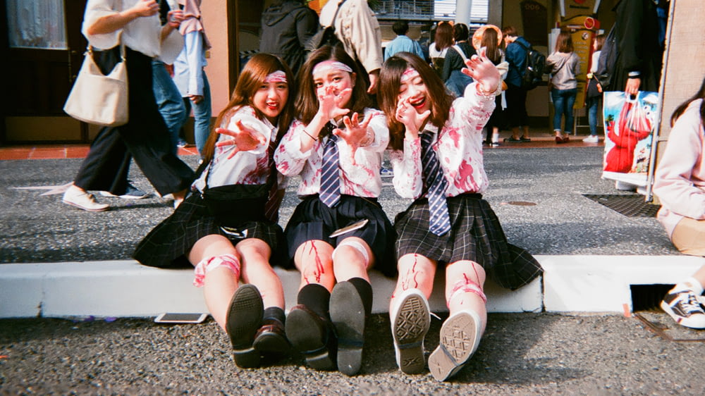 three school girls sitting on concrete ground