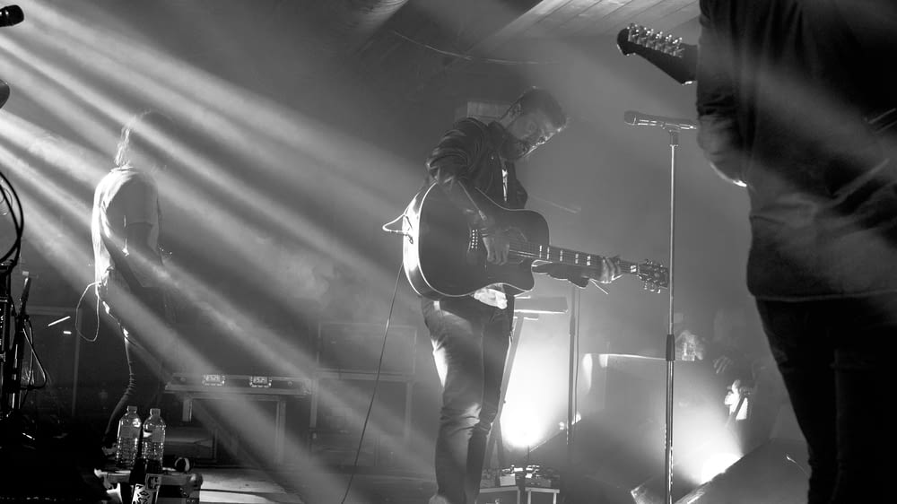 grayscale photography of band member performing on stage