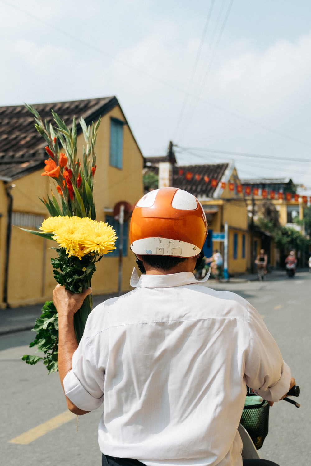 person riding motorcycle while holding yellow petaled flowers during daytime