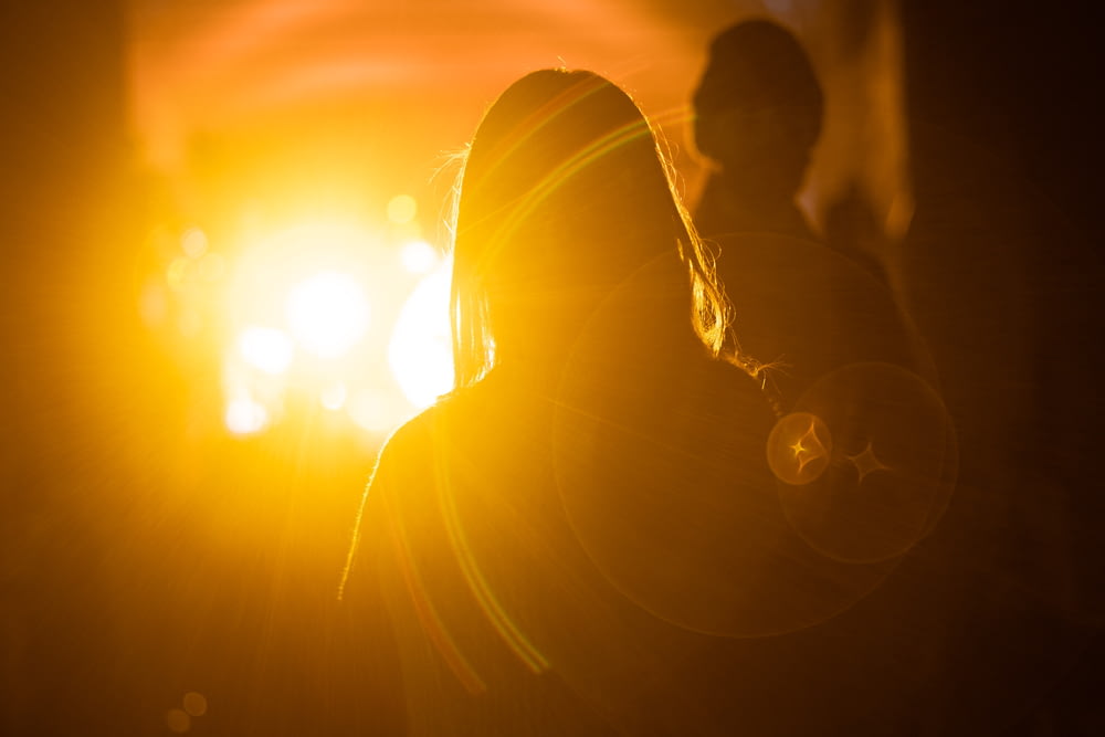 fotografia da silhueta da mulher na frente da luz laranja