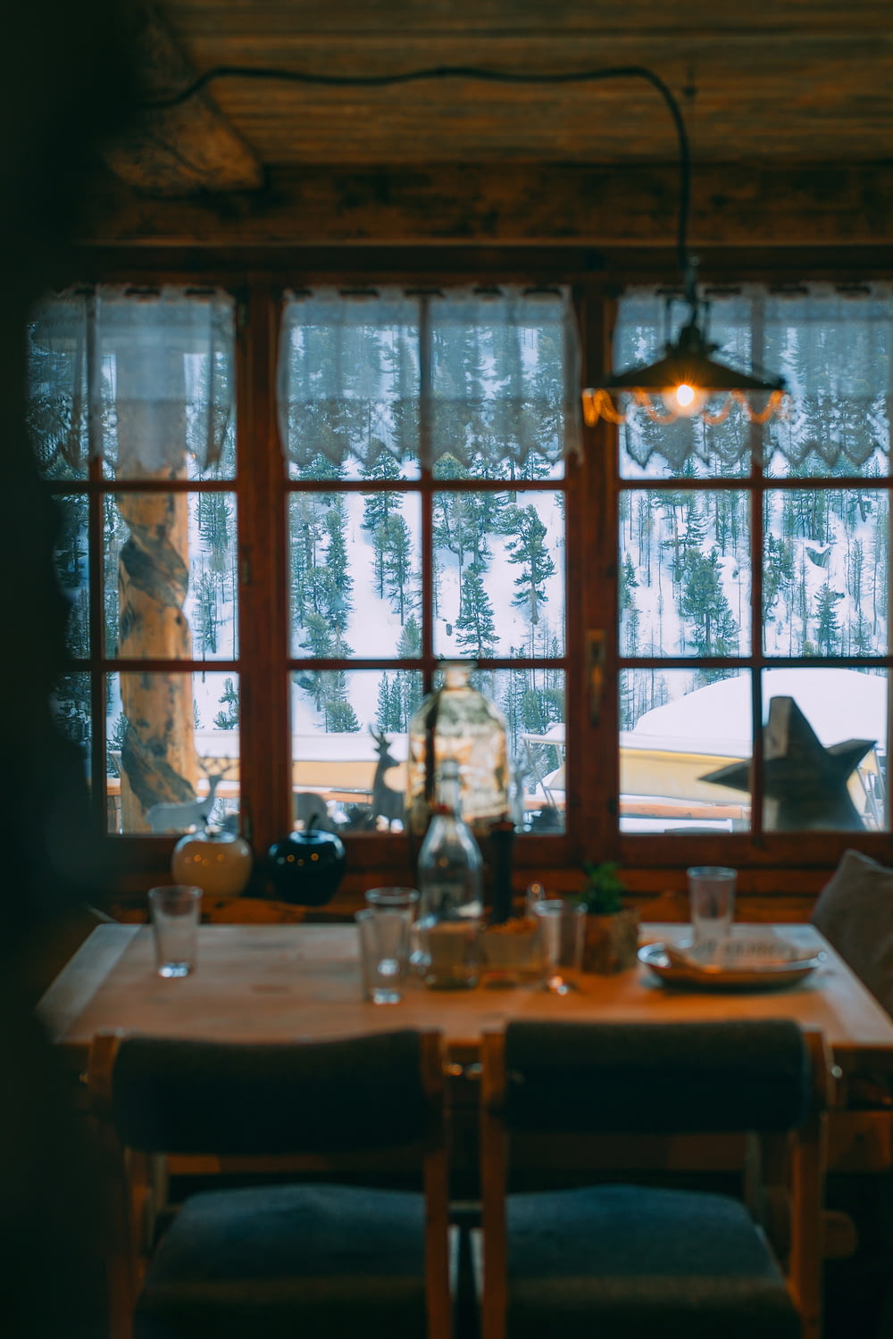 a dining room table with a view of a snowy forest
