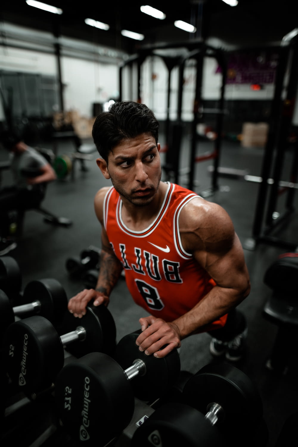 man in red Chicago Bulls jersey doing push-up exercise on dumbbells