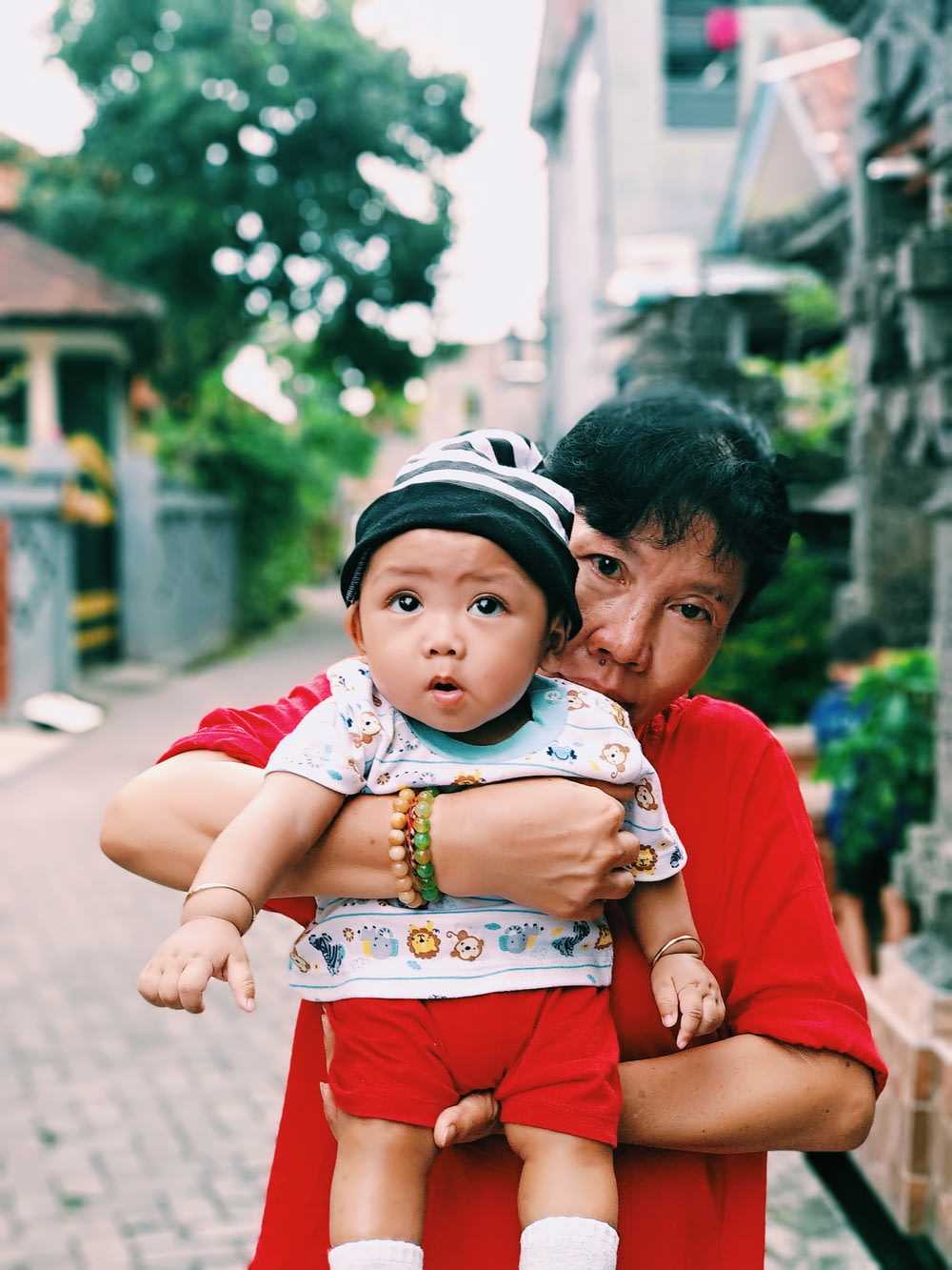 girl wearing red shirt carrying baby outdoor during daytime