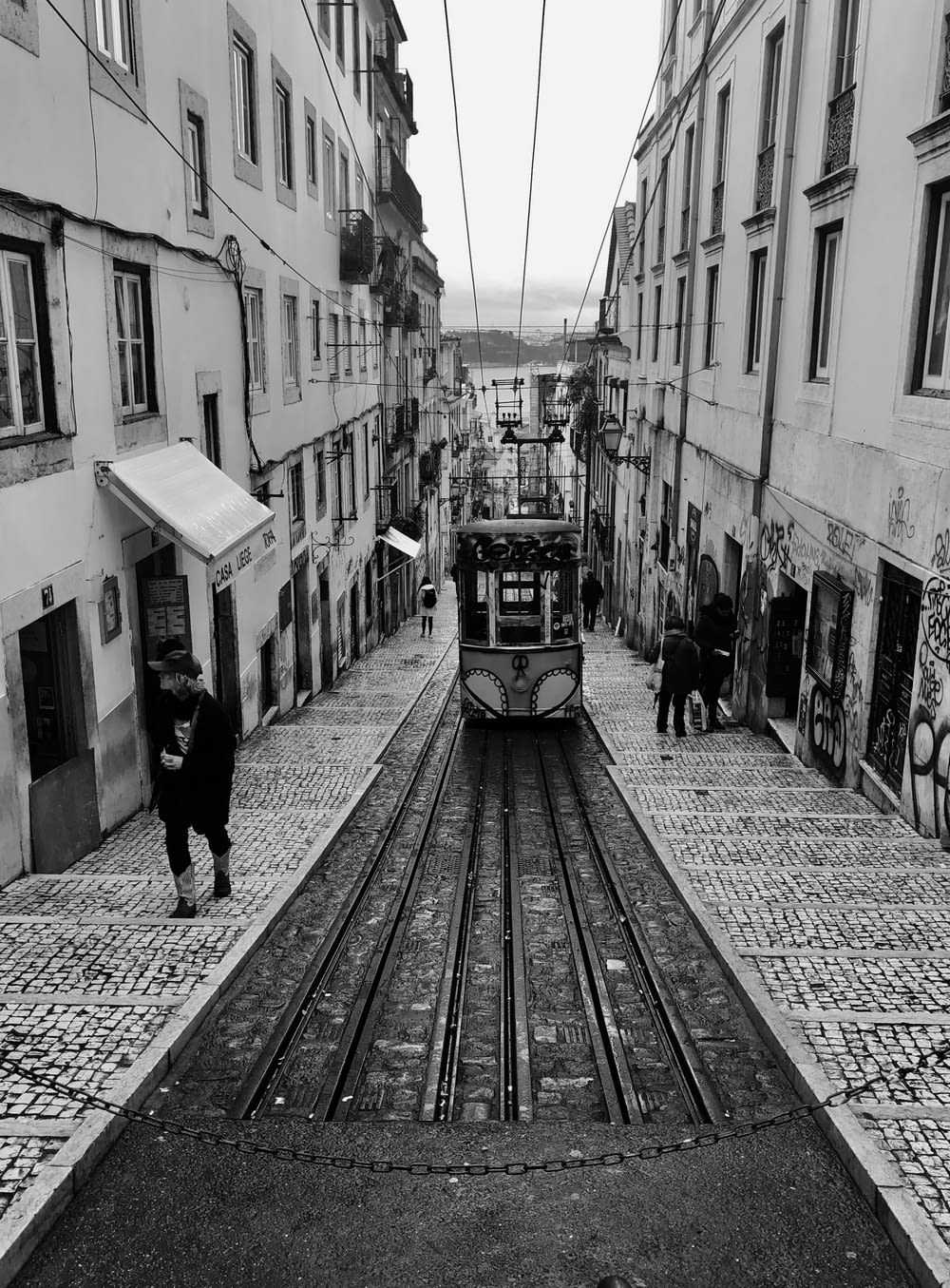 grayscale photography of tram passing through ascending alley