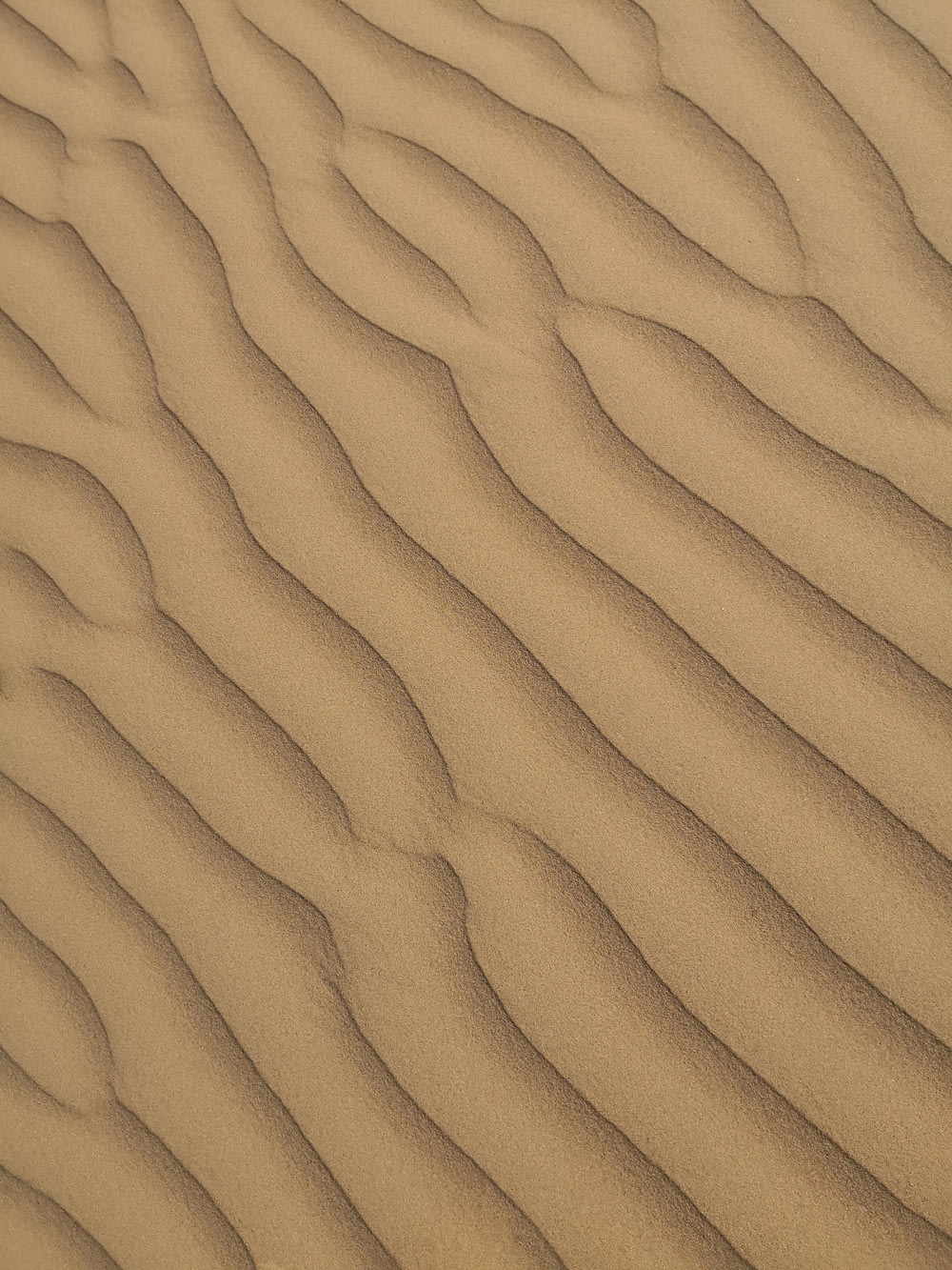 a sand dune with wavy lines in the sand