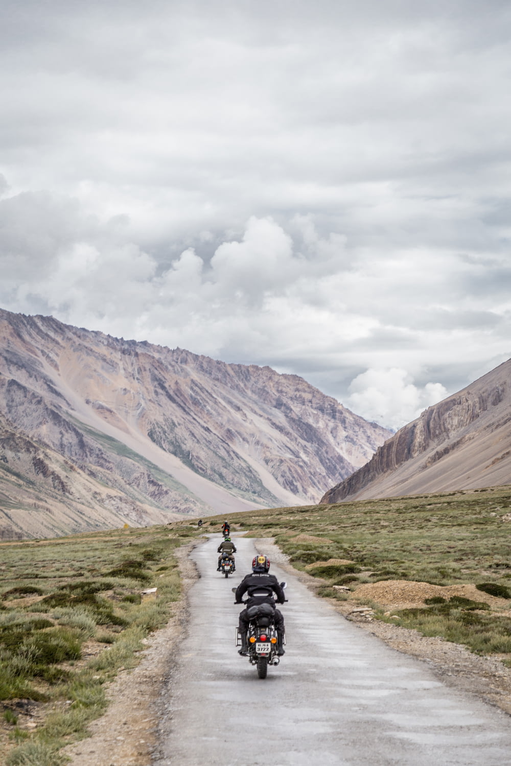 Dos motocicletas conduciendo por una carretera gris