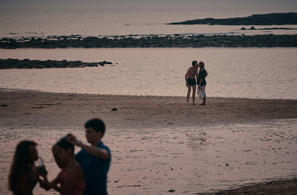 couple kissing on beach during daytime