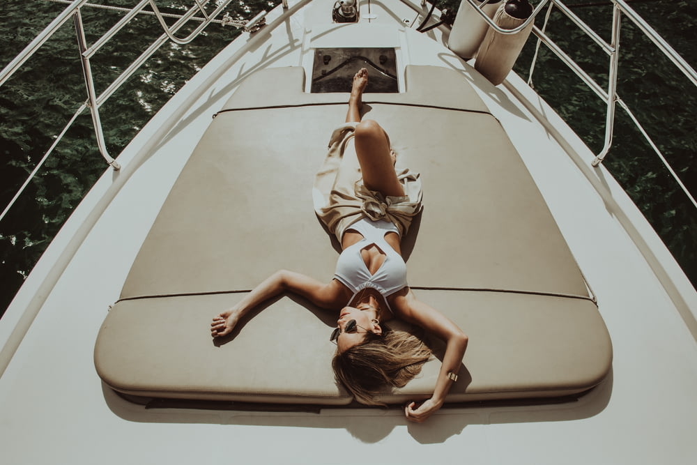 donna sdraiata su stuoia grigia su barca bianca