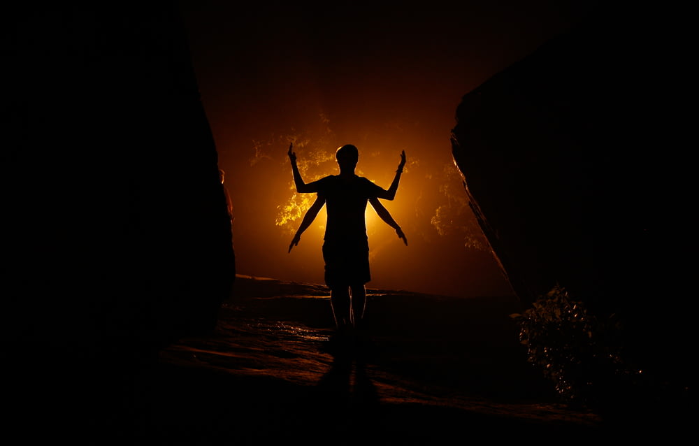 a person standing in the dark with their arms outstretched