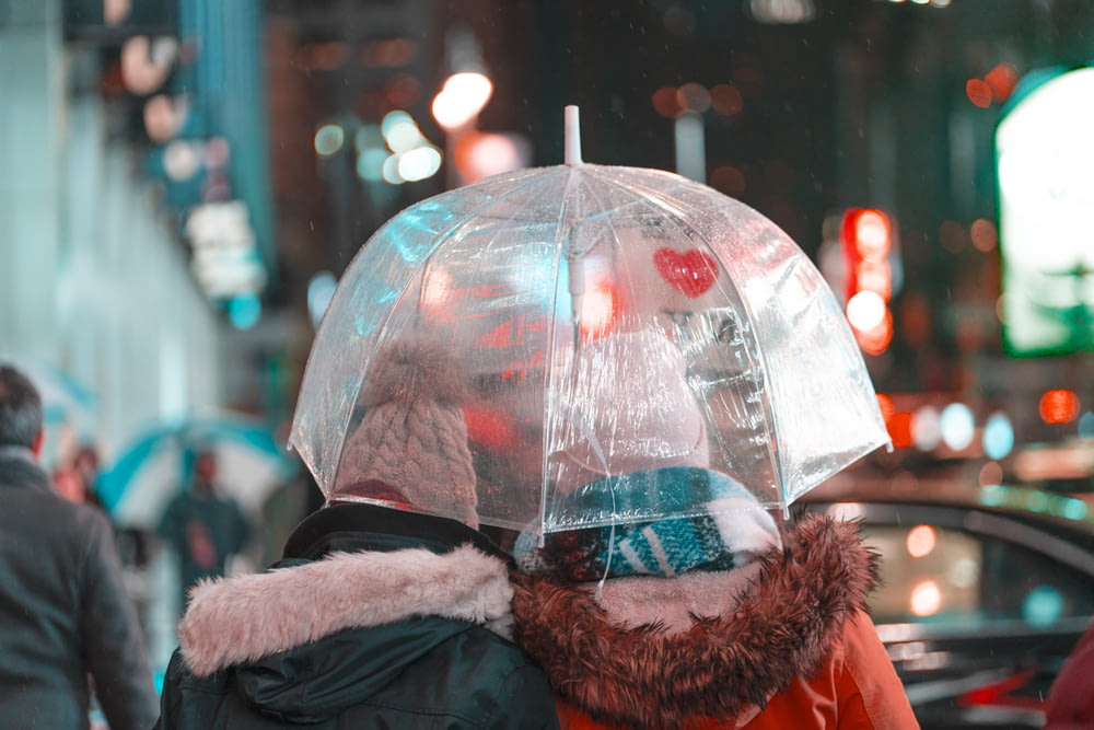 Due persone che indossano cappotto che tengono l'ombrello bianco