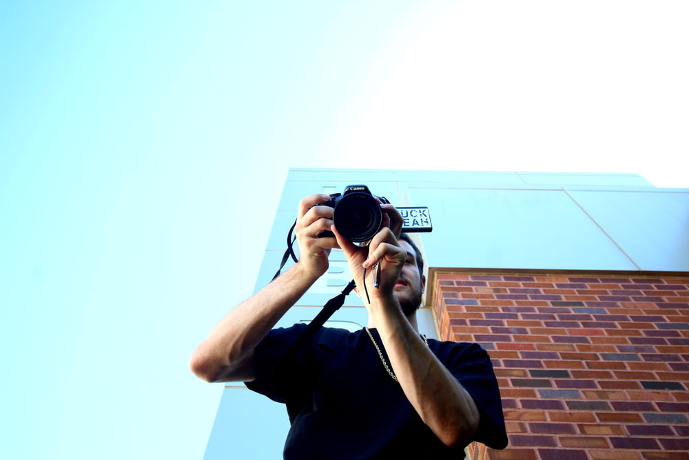 man standing and using DSLR camera