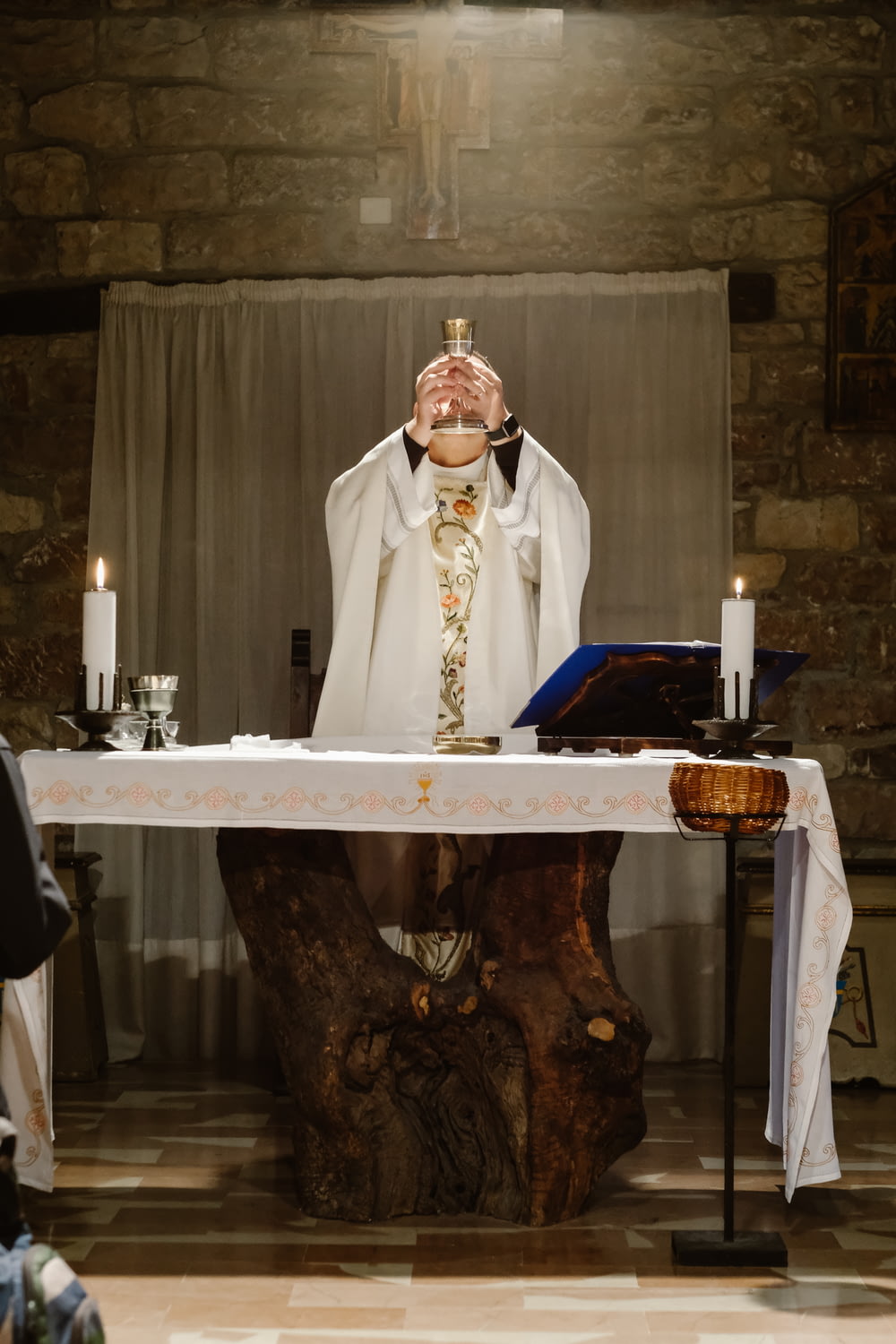 Priester hebt Becher an, während er neben dem Tisch steht